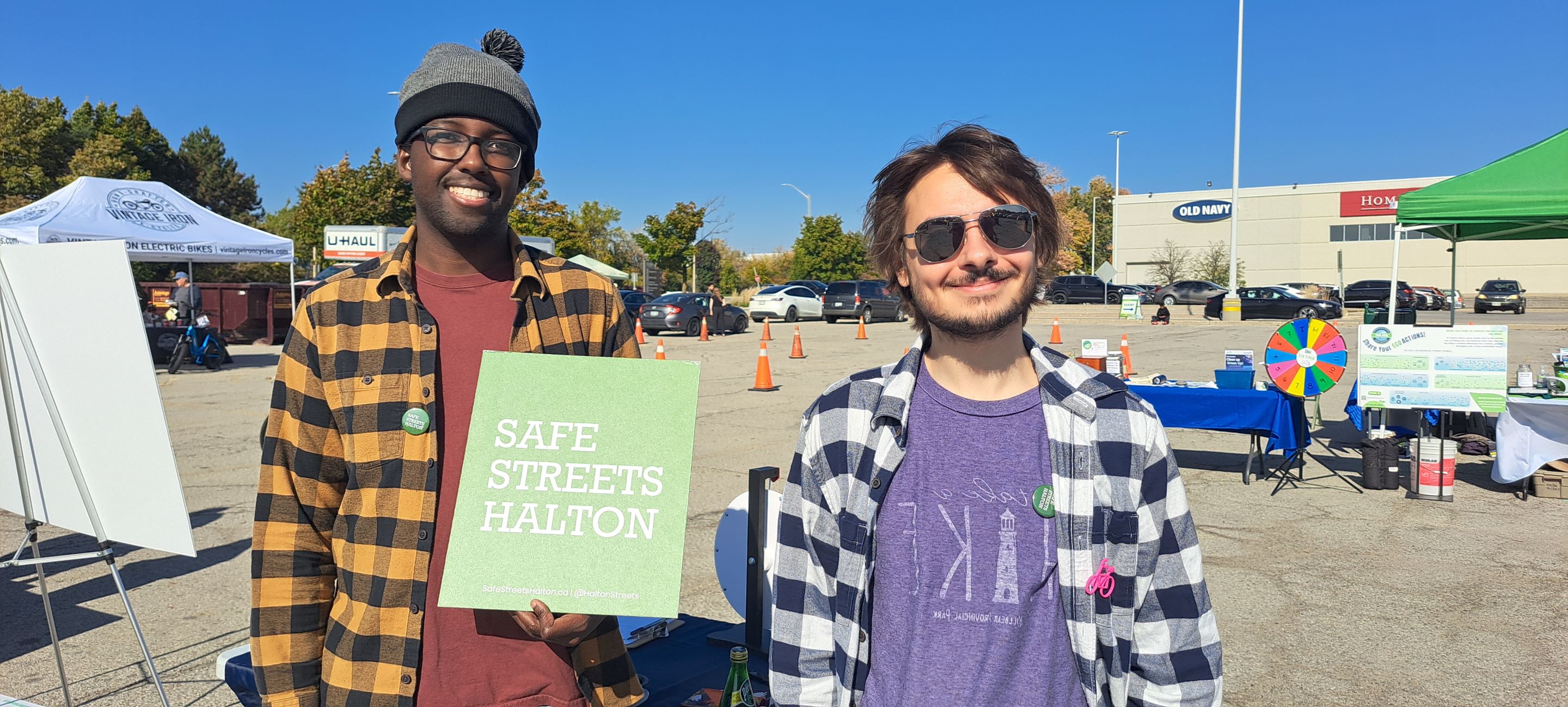 two people smiling at the camera, with on holding a Safe Streets Halton sign