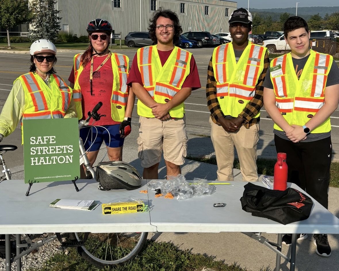 people in high-visibility vests at a table with a Safe Streets Halton sign on it